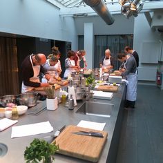 a group of people preparing food on top of a kitchen counter next to each other