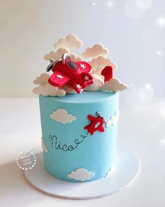 a blue cake with an airplane and clouds on it