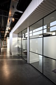 an empty room with lots of windows and white partitions on the wall, in front of a black ceiling