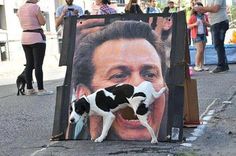 a painting of a man with a dog on the street next to it and people standing around