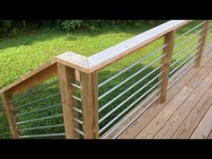 a wooden deck with metal railings and green grass in the backgroung