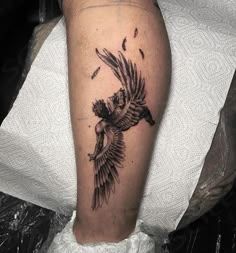 a black and white photo of a bird tattoo on the left leg, with birds flying around it