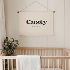 a baby crib with a white blanket hanging on the wall next to a potted plant