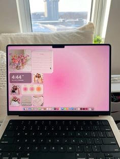 an open laptop computer sitting on top of a white table in front of a window