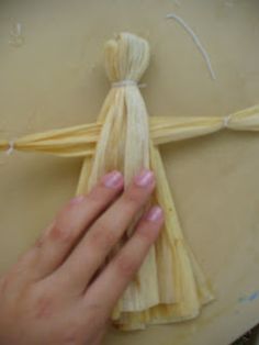 a hand holding a piece of pasta on top of a table next to a string