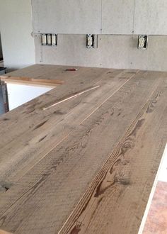 an unfinished kitchen counter top with white cabinets in the background and wood flooring on the other side