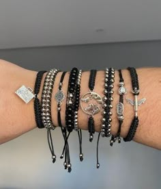 a woman's arm with several bracelets on it, including an anchor and cross