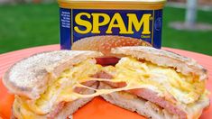 an orange plate topped with a sandwich and a can of spam