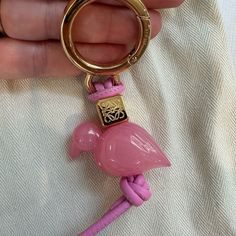 a pink flamingo keychain is being held by someone