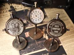 three small clocks sitting on top of a table next to an old newspaper page with the words happy anniversary written on it