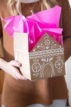 a woman holding a cardboard box with a house on it