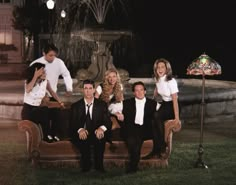 a group of people sitting on top of a couch in front of a fountain