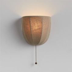 a wall light with a wooden shade hanging from it's side