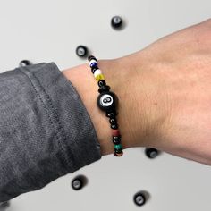 This bracelet is made with glass seed beads, crystal-like beads, and an 8-ball bead. The design is supposed to represent the 15 balls in both solids and stripes with the 8-ball in the middle. These bracelets are perfect for any billiards-loving person and can double as a good luck charm!  The picture shows it paired with other variations of the bracelet that can be found posted in our Etsy shop.  The bracelet is made in an average adult size but is stretchy and should fit just about anyone. Plea 8 Ball Crochet Beanie, 8 Ball Bracelet, 8 Ball Jewelry, 8 Ball Jewelry Dish, 8 Ball Pool Shirts, Swift Bracelets, Solid And Striped, 8 Ball, Ball Bracelet