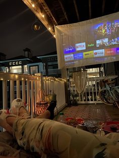 a person laying on a couch in front of a large screen with people watching it