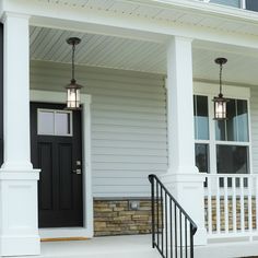 the front porch of a white house with black doors