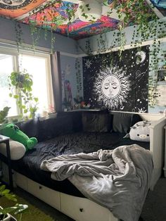 a bed room with a sun mural on the wall and plants hanging from the ceiling