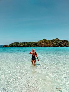 a woman wading in shallow water near an island