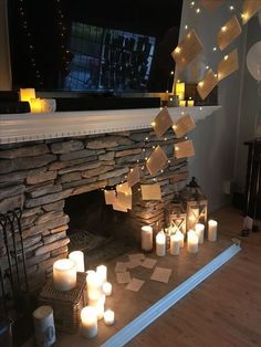 candles are lit in front of a stone fireplace