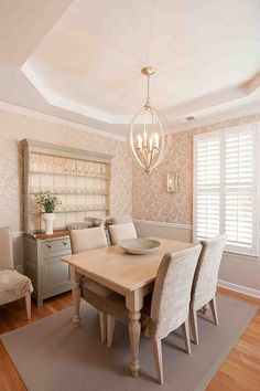 a dining room table with chairs and a light fixture hanging from it's ceiling