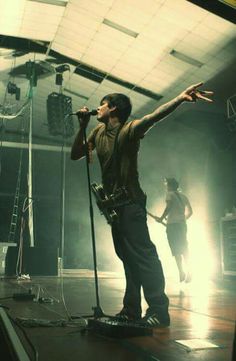 a man standing on top of a wooden floor holding a microphone in front of him