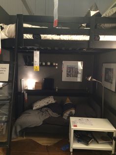 a bunk bed with a desk underneath it in a room that is dark and cluttered