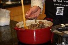 a person stirring food in a pot with a ladle next to it on the counter