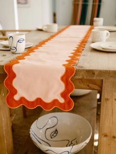 an orange and white table runner sitting on top of a wooden table next to a bowl