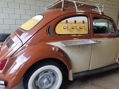 an orange and white car parked in a garage next to a brick wall with metal bars on the roof