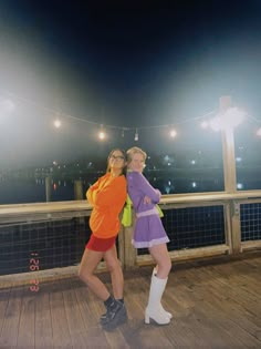 two women standing on a deck at night with their arms around each other's shoulders