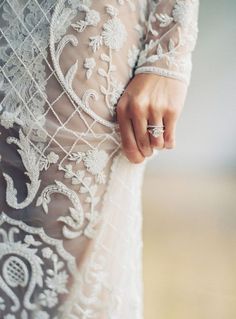 a close up of a person's hand on the back of a wedding dress