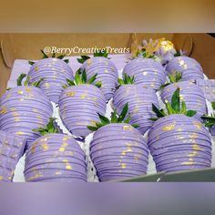 there are many purple strawberries with gold sprinkles on them in a box