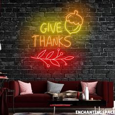 a red couch sitting in front of a brick wall with a neon sign that says give thanks