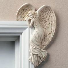 an angel statue hanging on the side of a wall next to a white window frame