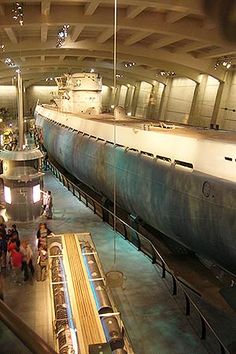 a large boat is on display in a museum while people look at it from the other side