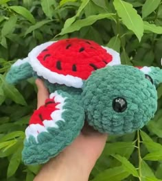 a hand holding a small stuffed animal that looks like a watermelon on it's back