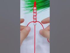 a person holding a red string with green hair on it