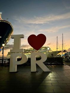 a large sign that says i love pr with a boat in the back ground behind it