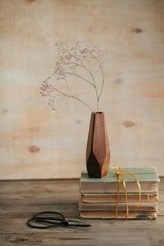 a wooden vase sitting on top of books next to a pair of scissor