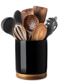 a black cup filled with kitchen utensils and wooden spoons