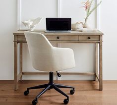 a desk with a laptop on it next to a flower vase and potted plant