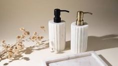 two white soap dispensers sitting next to each other on a counter top