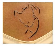 a woman's back with a small tattoo on the side of her stomach that has a drawing of a mother and child in it