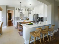 a kitchen with white cabinets and an island in the middle is surrounded by wooden chairs