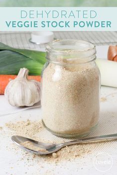 a glass jar filled with veggie stock powder next to garlic and carrots