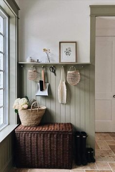 an entryway with baskets and hooks on the wall next to a basket filled with flowers