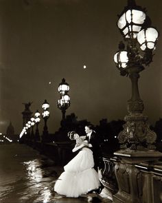 an old black and white photo of a bride and groom on a bridge at night