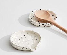 two bowls and a wooden spoon on a white surface with black dots, one has a wood spoon in it