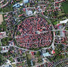 an aerial view of a city with lots of red buildings and green grass in the foreground