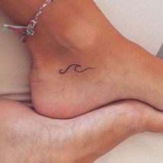 a woman's foot with a small wave tattoo on it